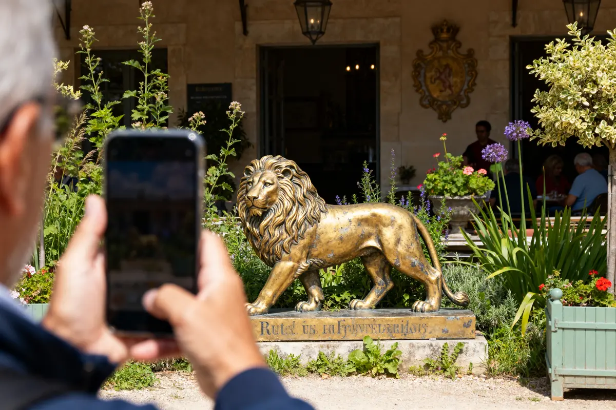 Personne photographiant une sculpture dorée de symbole du lion devant un restaurant fleuri